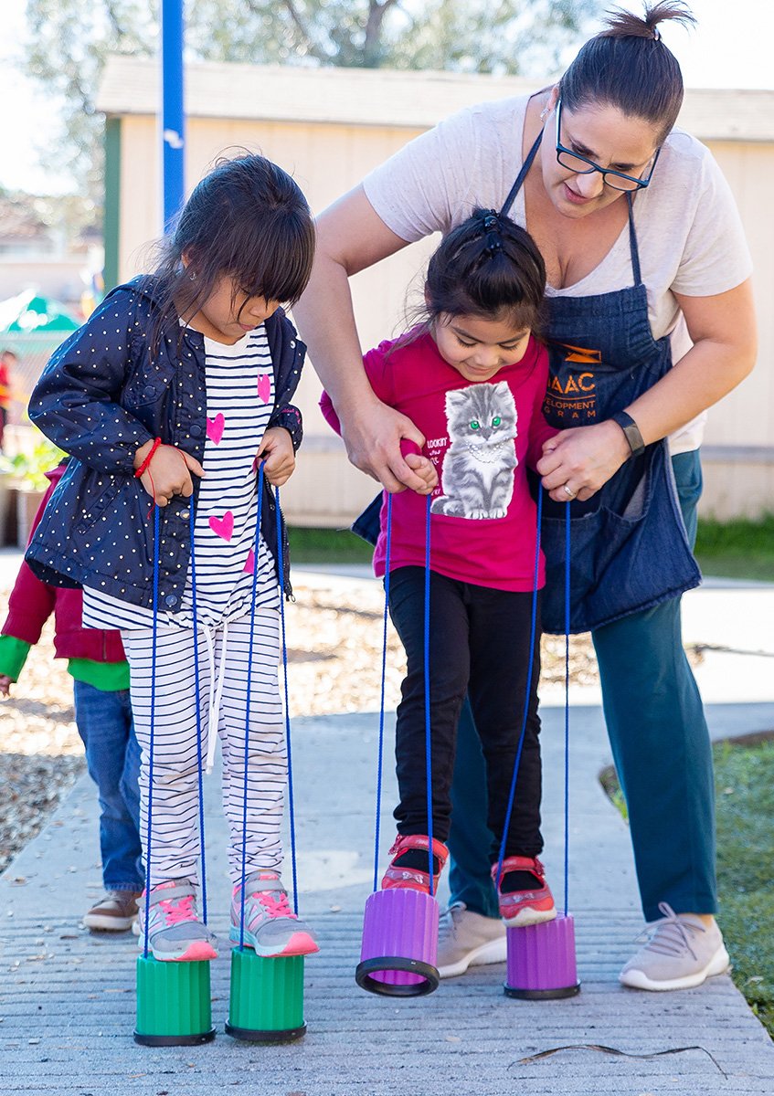 A woman and two girls playing with string.