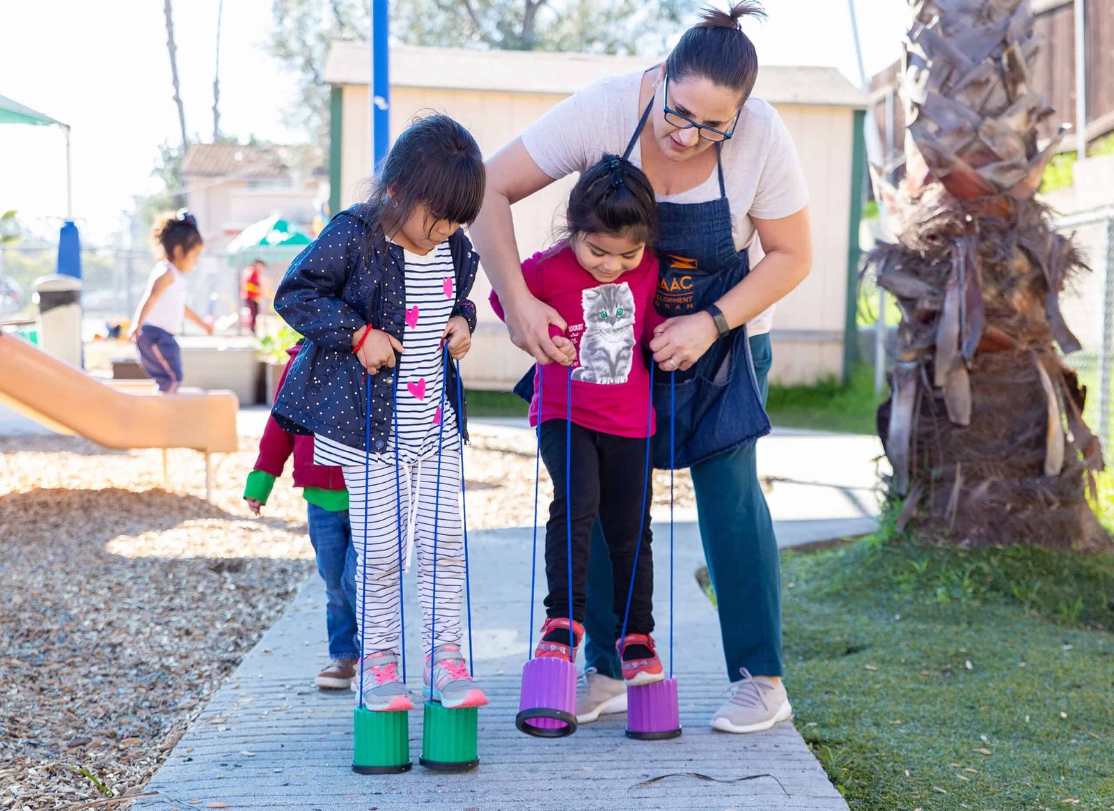 SANTURCE PARK CONSERVANCY INC PARK CONSERVANCY INCchild care A woman and two children playing with toy on sidewalk.