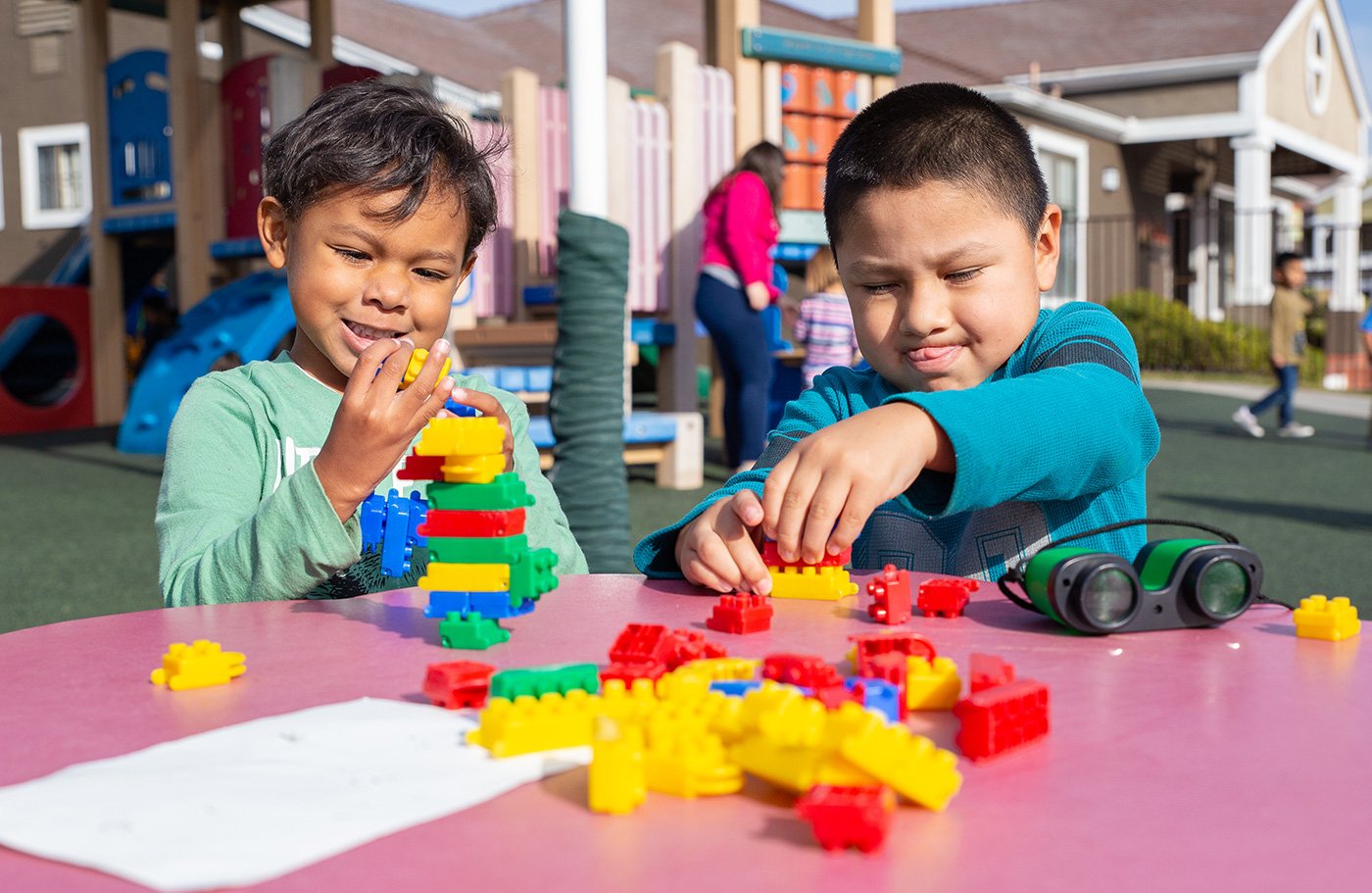 Two children playing with blocks at a table.