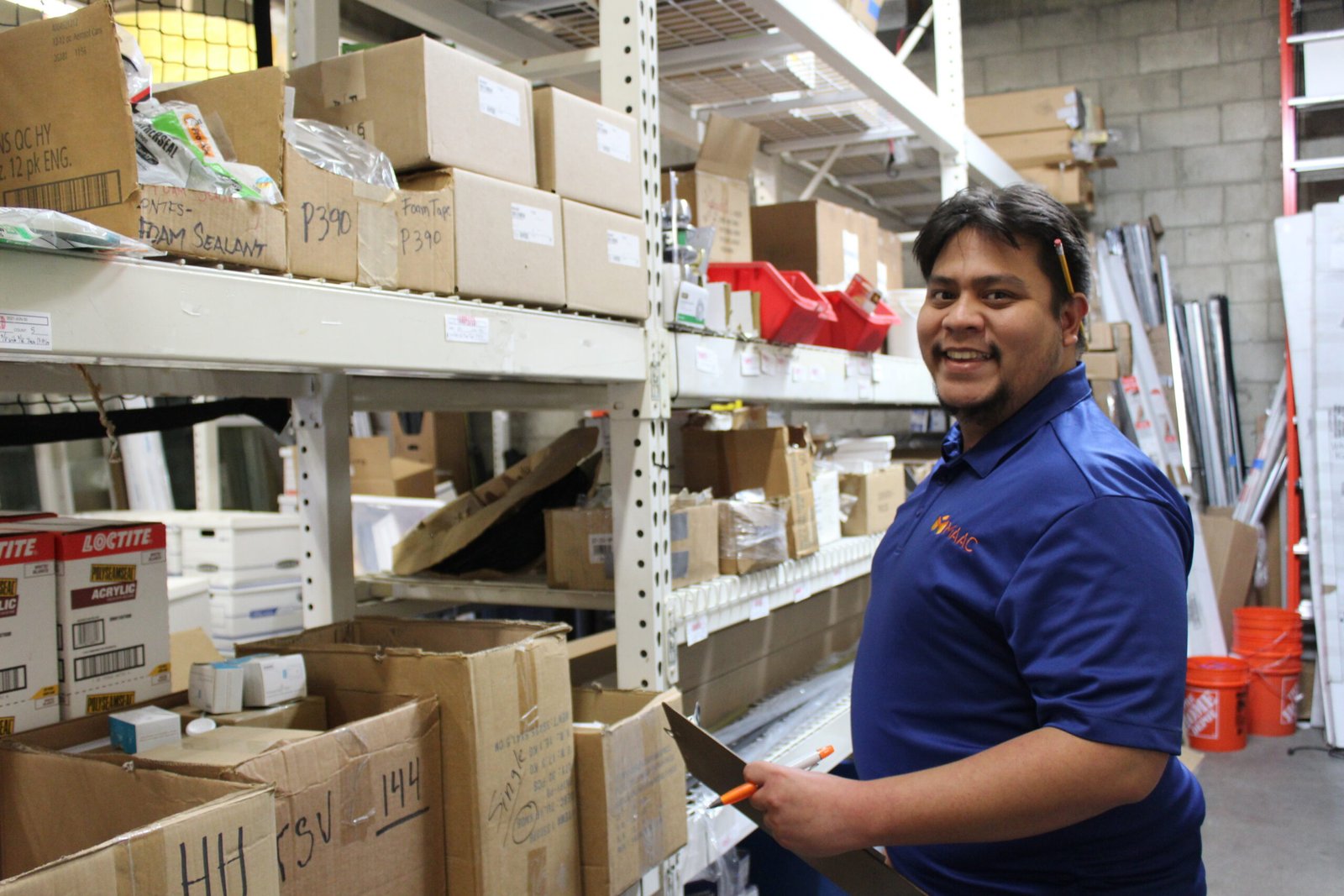 MAAC team member Weatherization A man holding an orange knife in front of boxes.