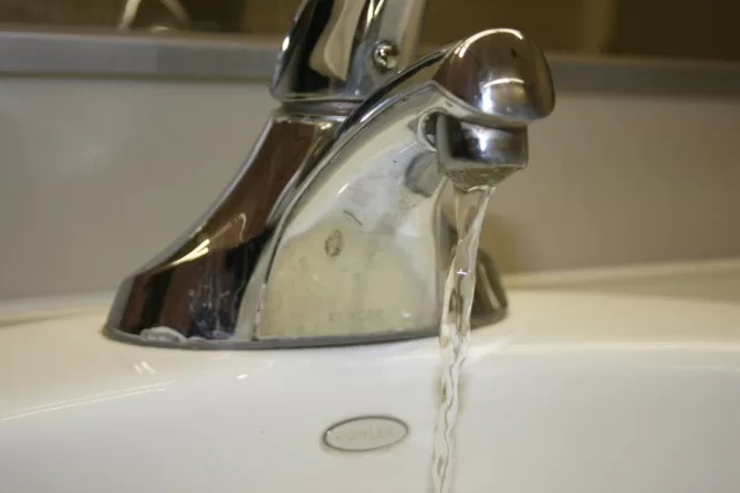 A faucet that is leaking water from the sink.