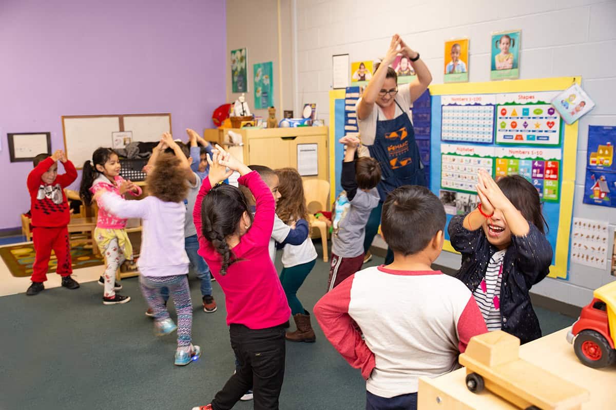 A group of children in the classroom doing different things.