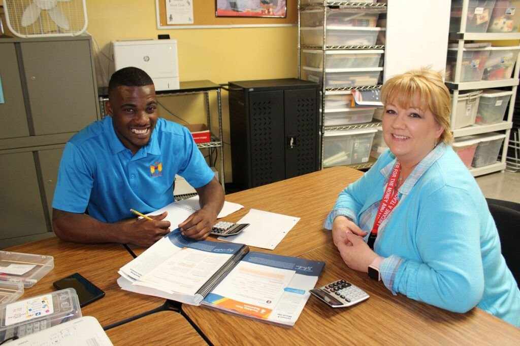 Two people sitting at a table with papers on it