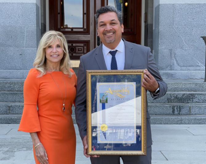 A man and woman holding up a framed certificate.