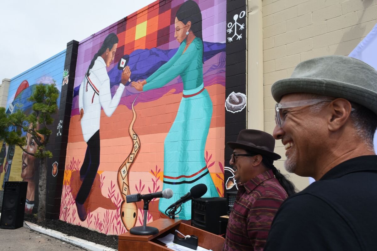 Two men standing in front of a mural.