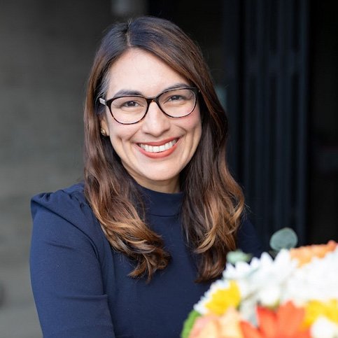 A woman with glasses and a bouquet of flowers.