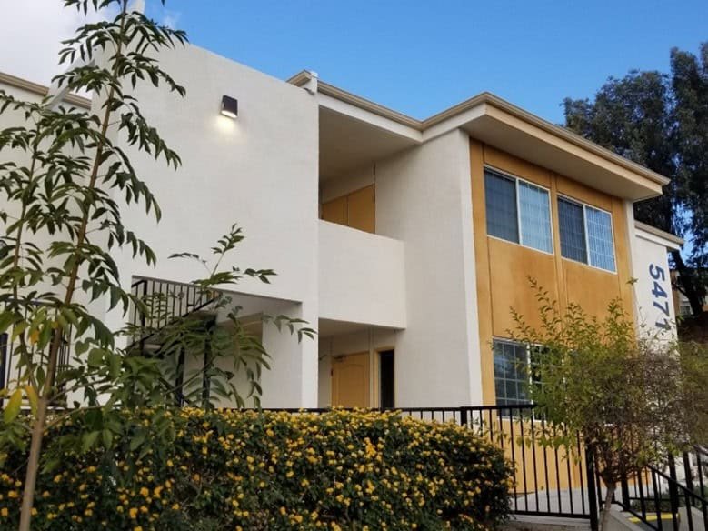 Hillside Apartments A building with yellow flowers and bushes in front of it.