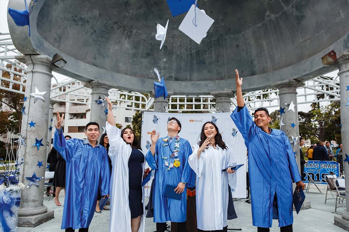 maac-graduates A group of people in graduation attire throwing their hats.