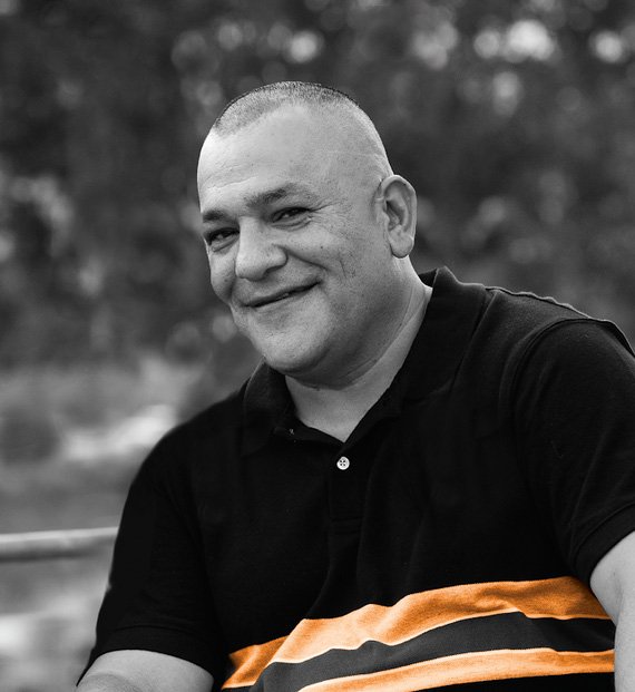 A man with bald head and black shirt smiling.