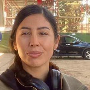 A woman standing in front of a car.