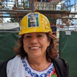 A woman wearing a yellow hard hat and smiling.