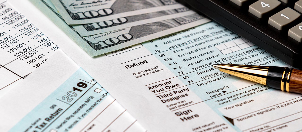 1040 income tax return form 2019 with money, calculator, and pen A close up of the irs tax form and money.